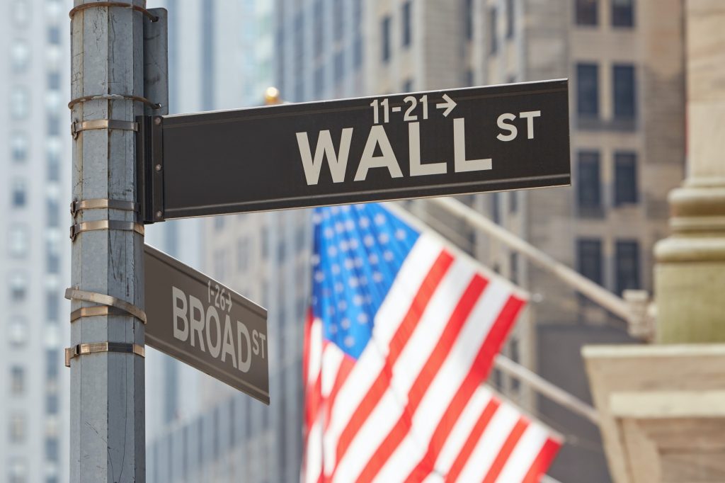 Wall Street sign near Stock Exchange with US flags, New York